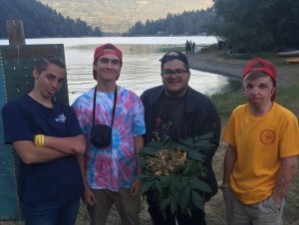 Four young men standing in front of a lake