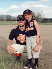 Father and daughter wearing baseball uniforms smiling