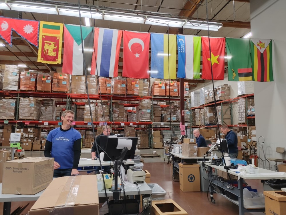 Four volunteers in a warehouse packing donation boxes