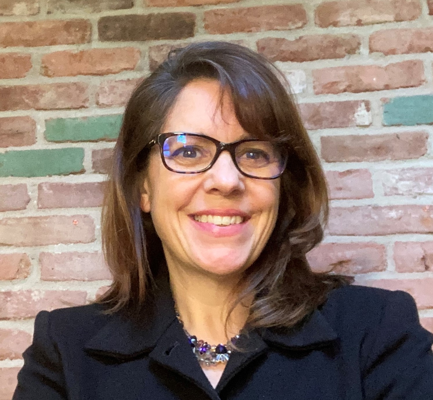 Headshot of women in blazer wearing glasses