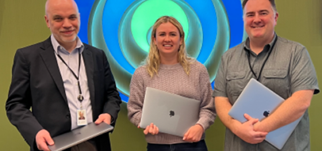 Three smiling people holding laptops