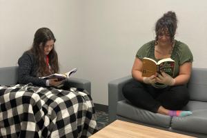 two women reading books on couch