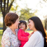 Grandmother, mother and daughter embracing and smiling in a park