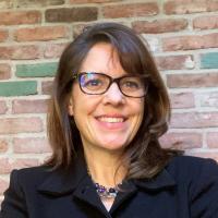 Headshot of women wearing blazer and glasses