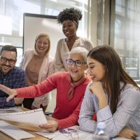 Five coworkers gathered around a computer working on a project