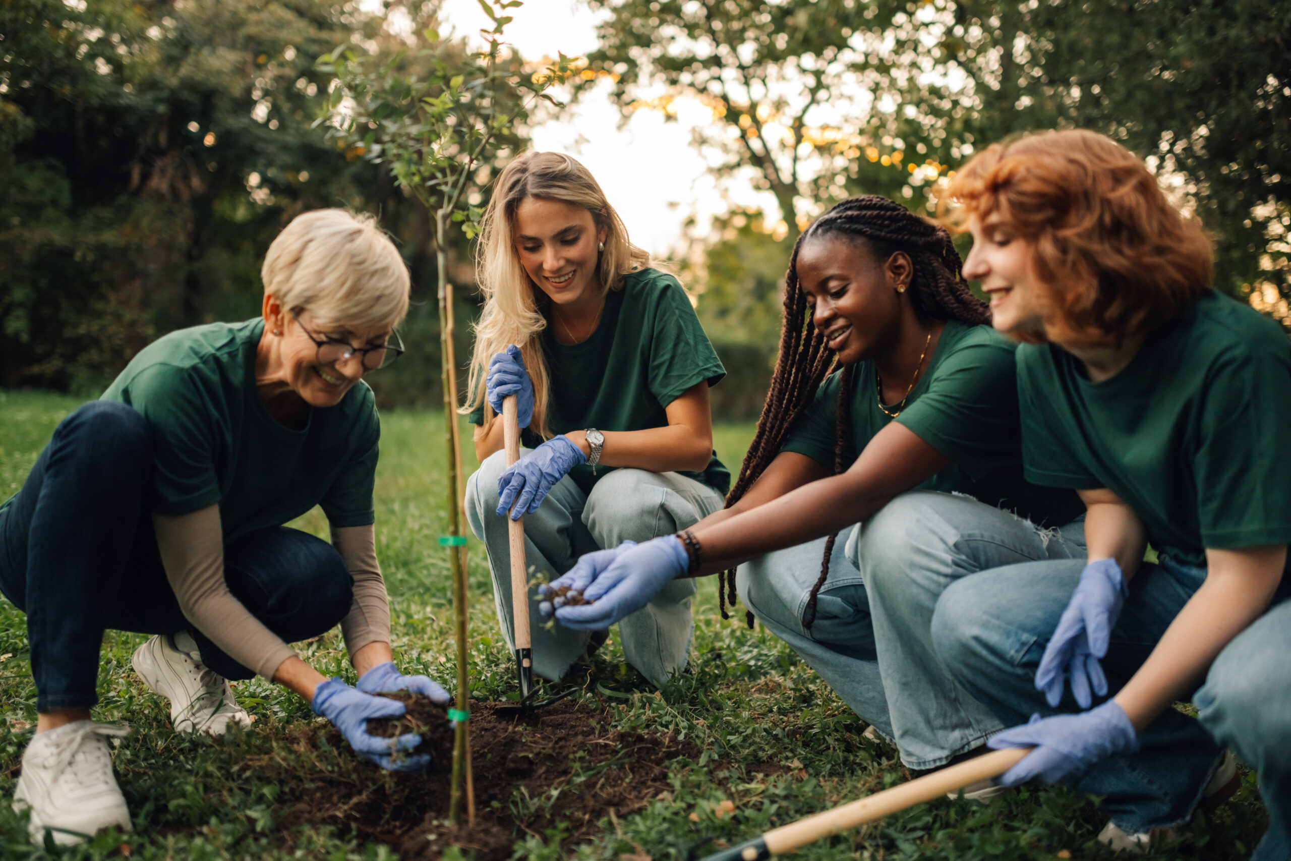 Group of four women in green shirts planting a tree